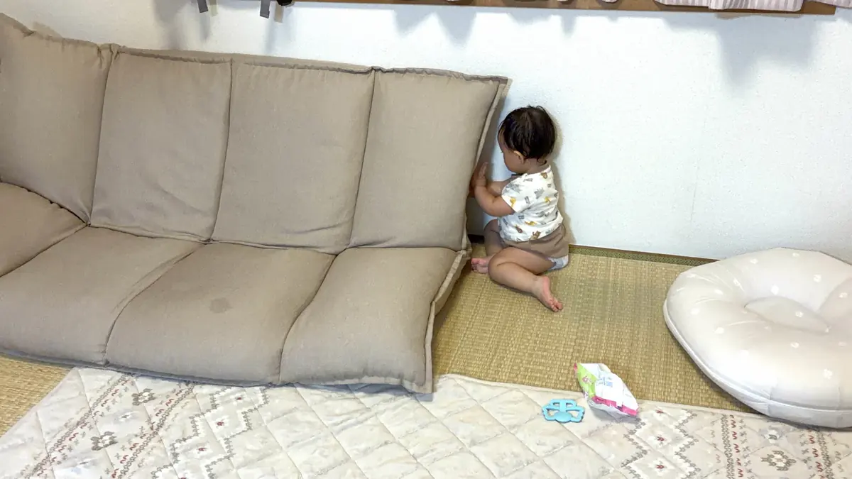 ソファと壁のすき間をのぞきこむ1歳3ヶ月の娘