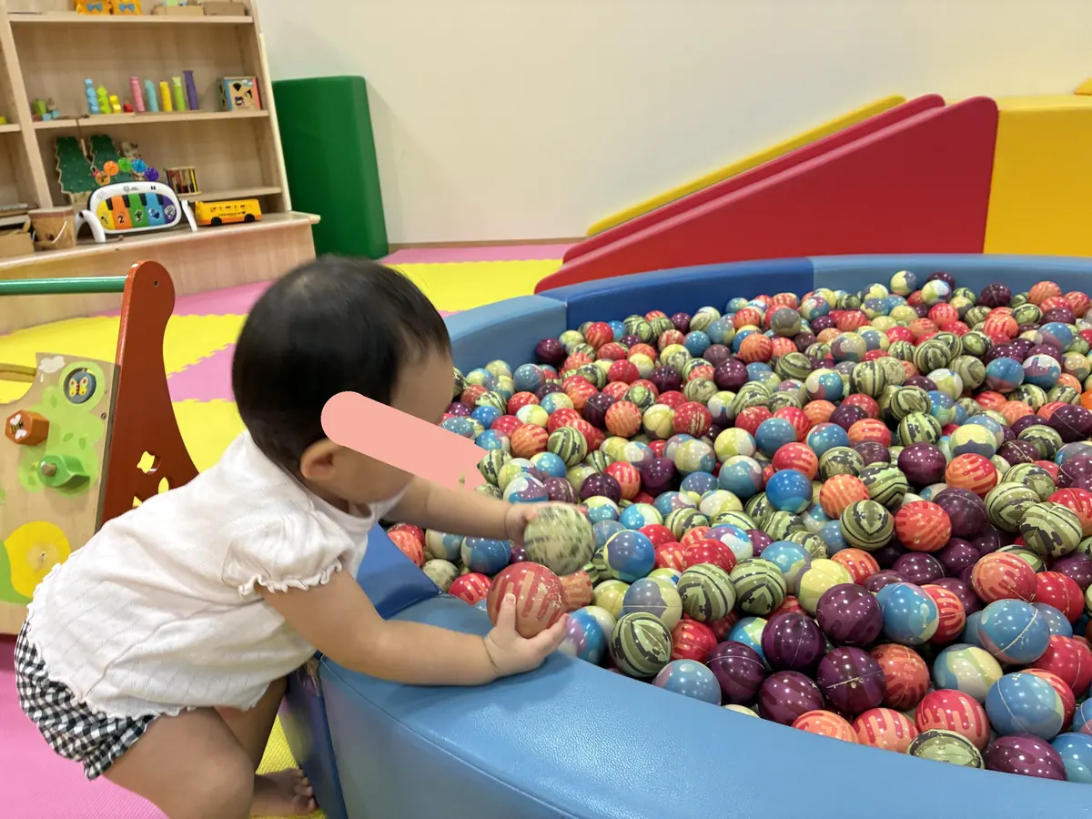 0〜2才コーナーのボールプールでボールをつかむ1歳の娘