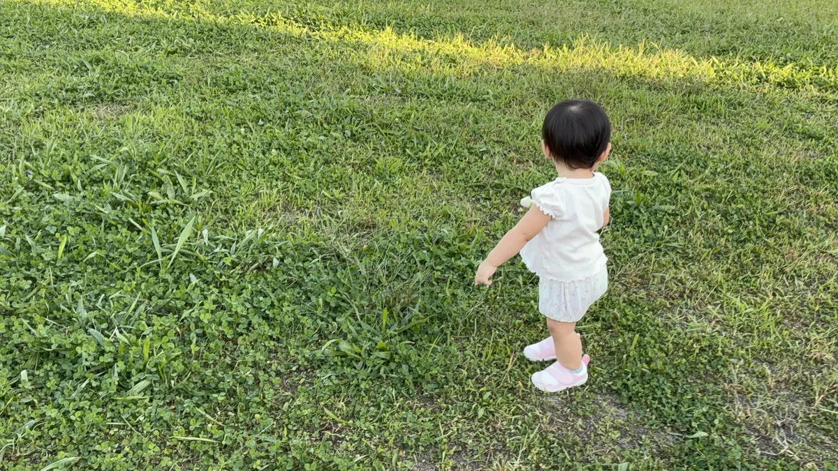 草の上で立ち止まる娘の後ろ姿